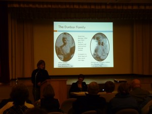 Jennifer talking about the Dunbars; on the left a picture of Albert Dunbar is seen, and Lafayette Dunbar is on the right.